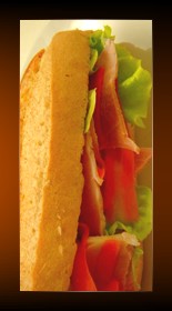 sandwich jambon tomates avec salade dans une baguette de pain.